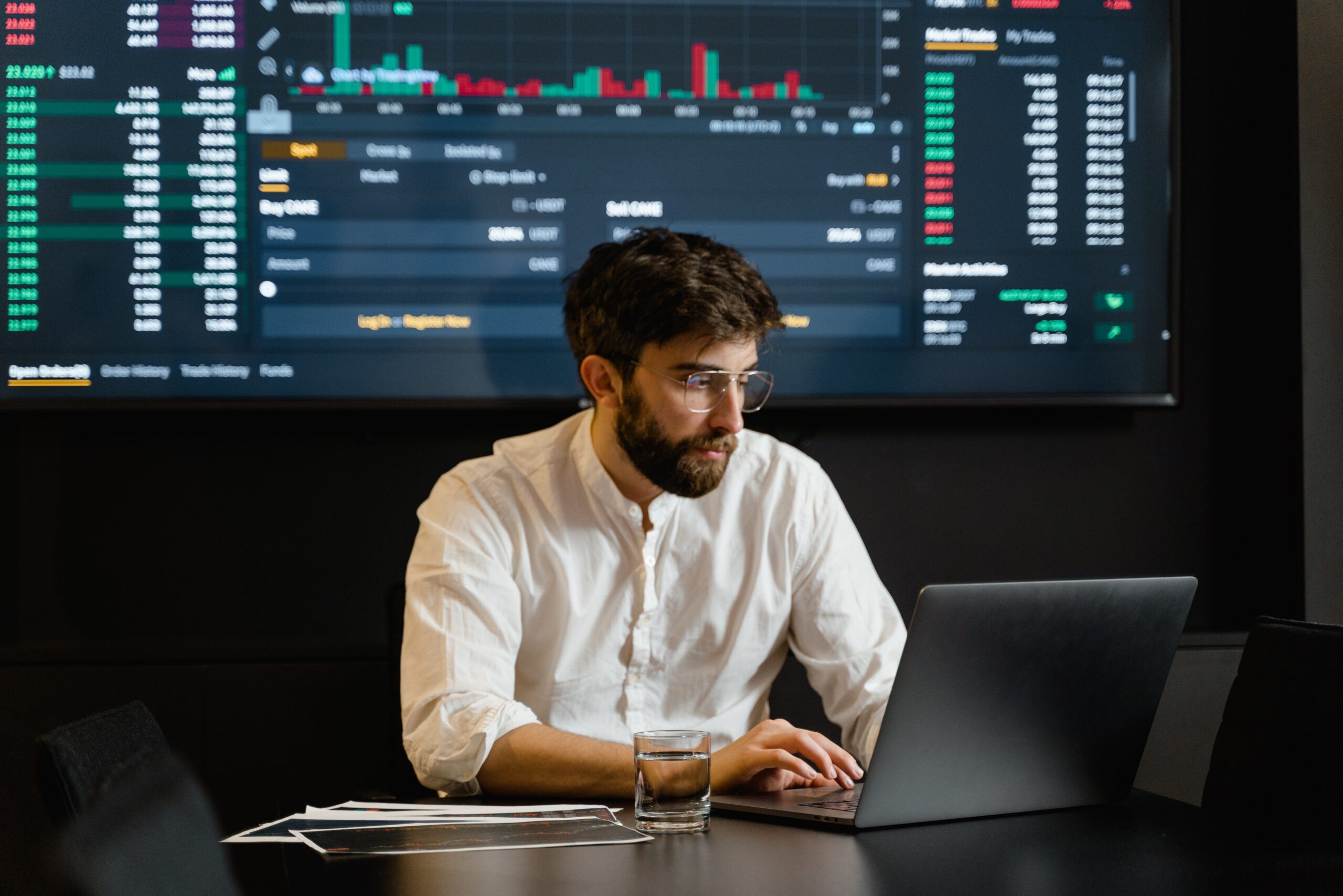 Homem de camisa branco com computador no escritório e tela de computador com códigos do Google ao fundo.